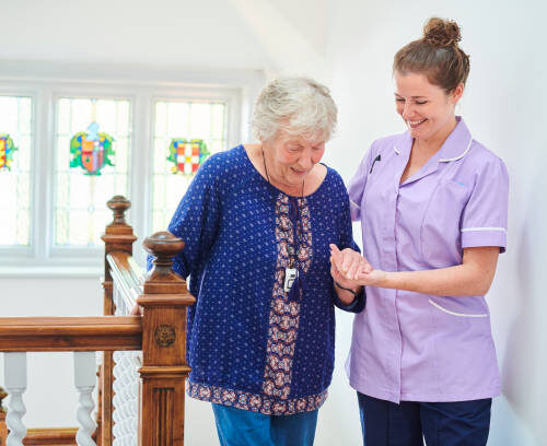 a nurse helps senior woman climb the stairs of the nursing home