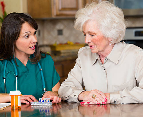 A healthcare provider talking to a senior woman in her home.